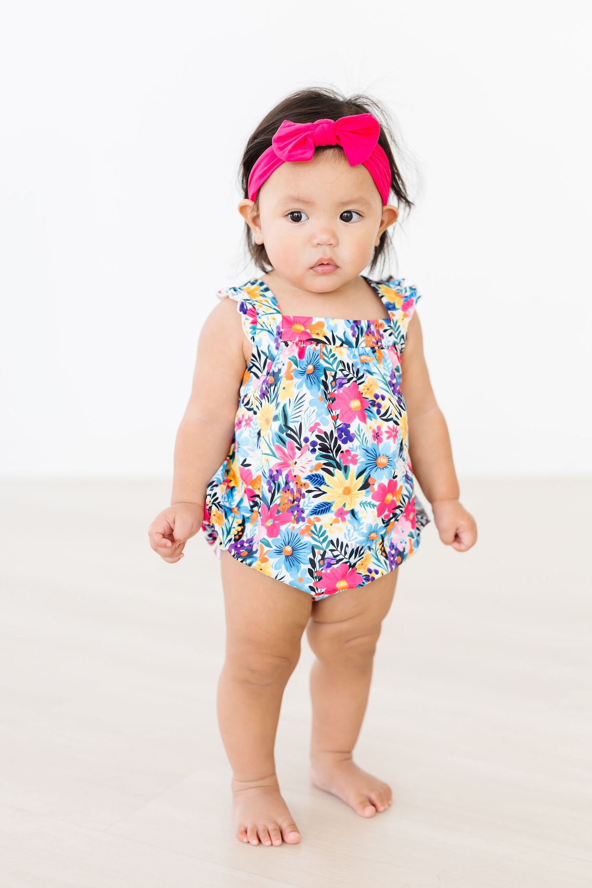 a baby girl wearing a flowered dress