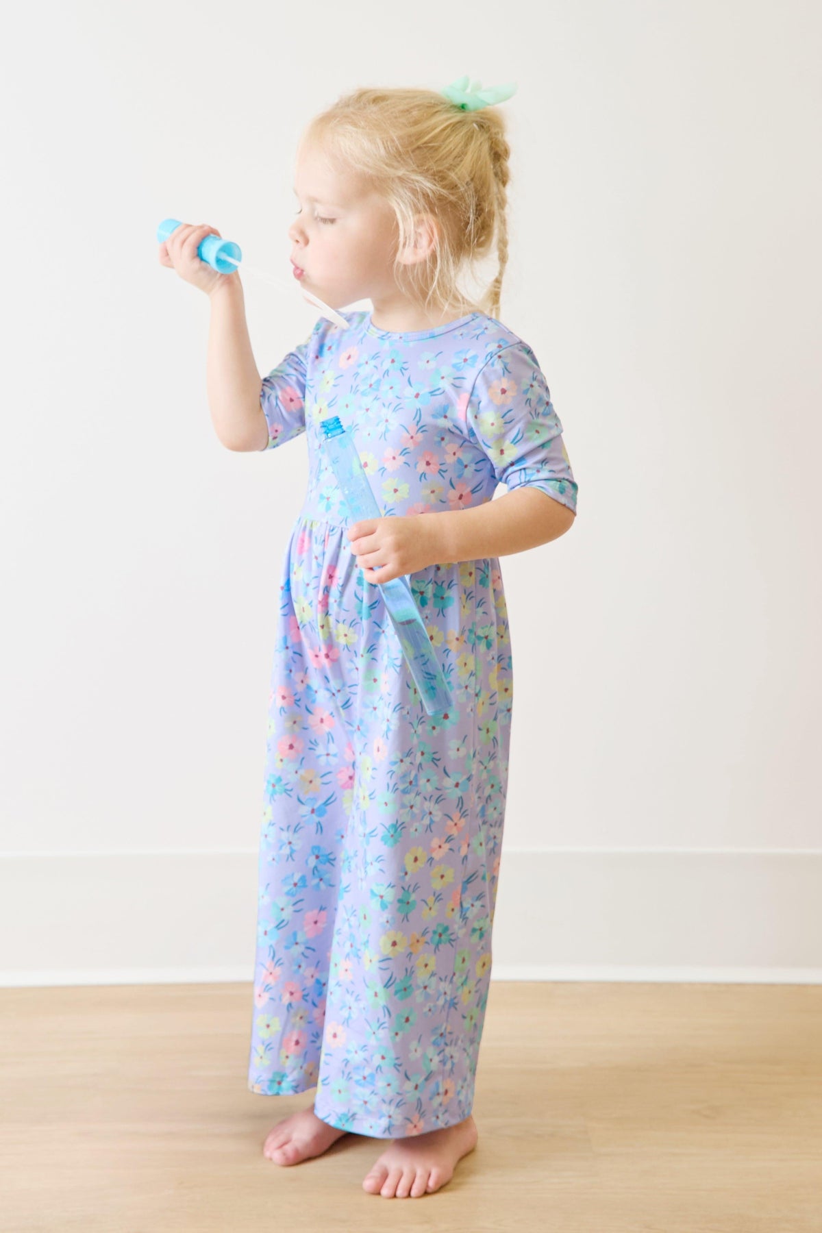 a girl in a dress blowing bubbles