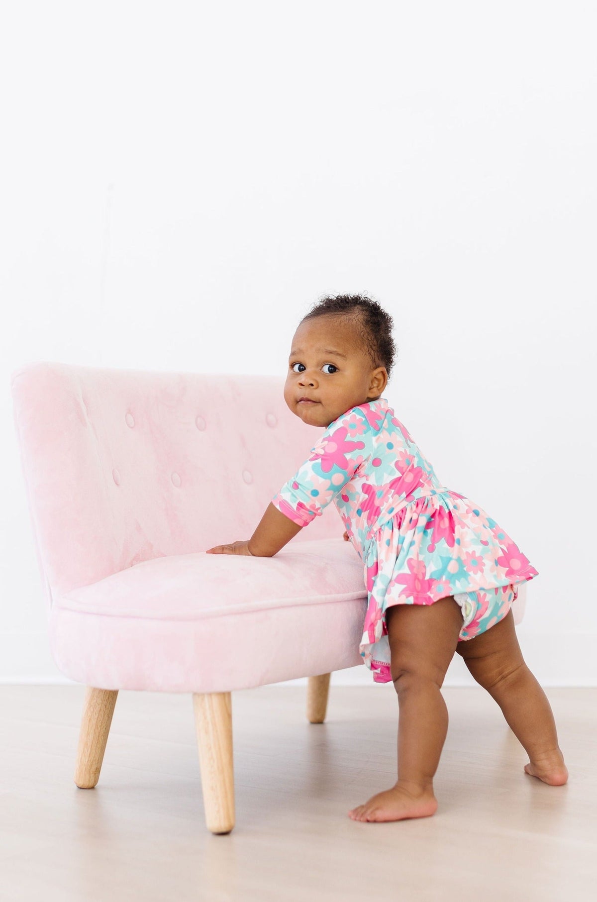 a baby standing on a pink couch