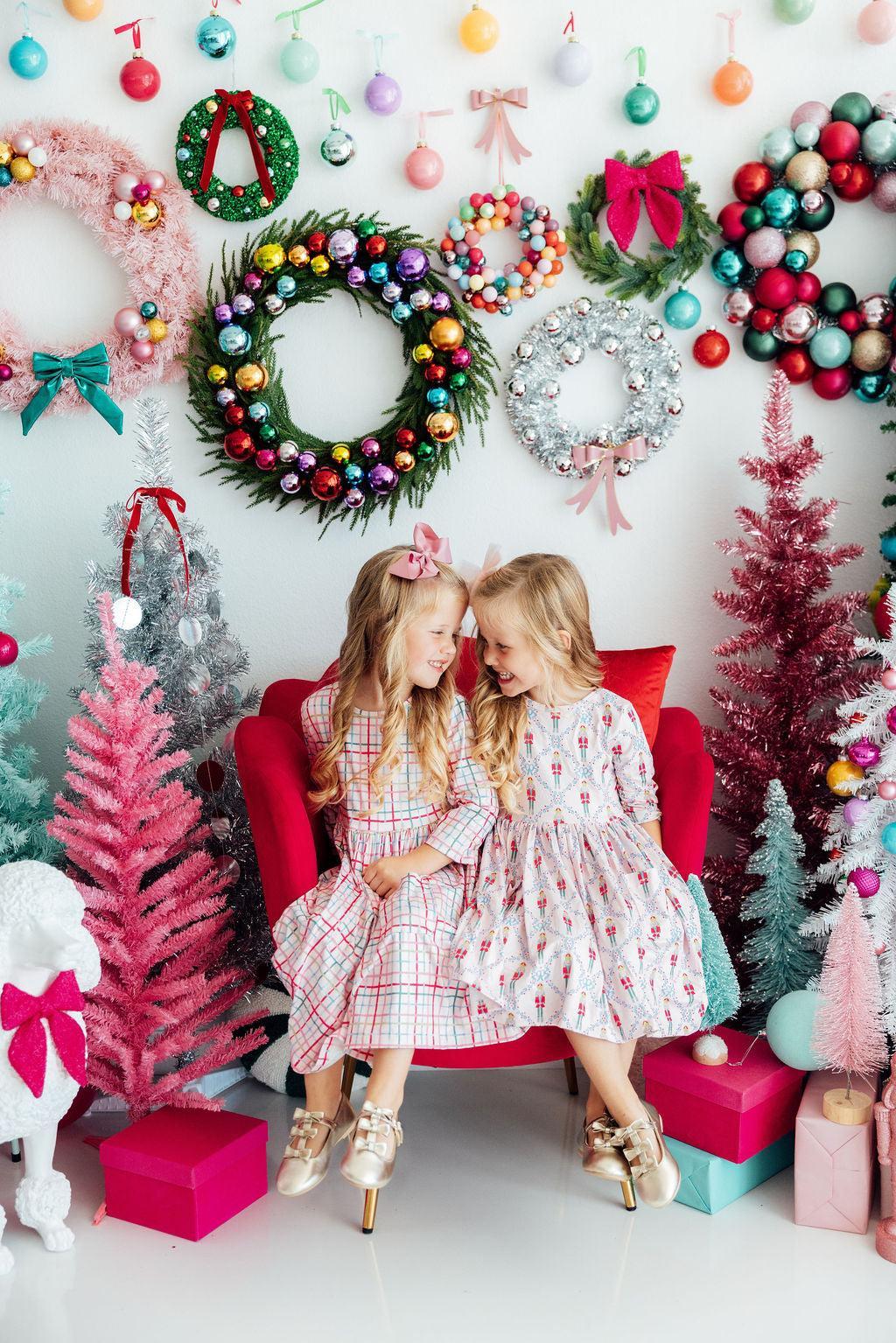 two girls sitting in a chair in front of a decorated wall