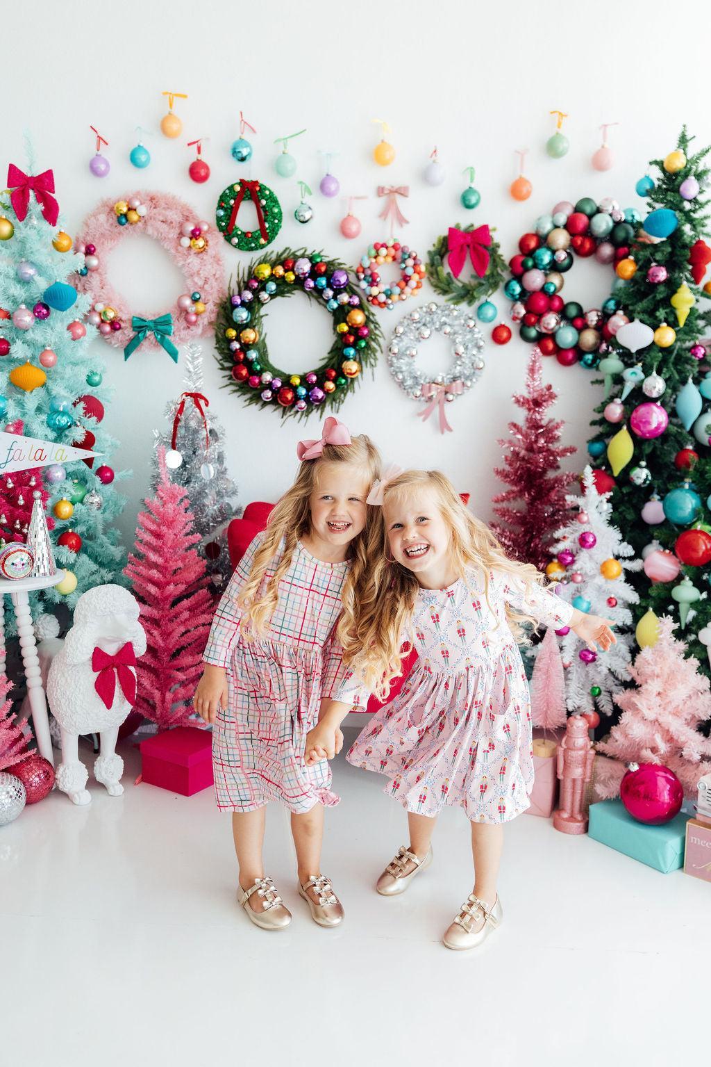 two girls posing for a picture in front of a decorated christmas tree