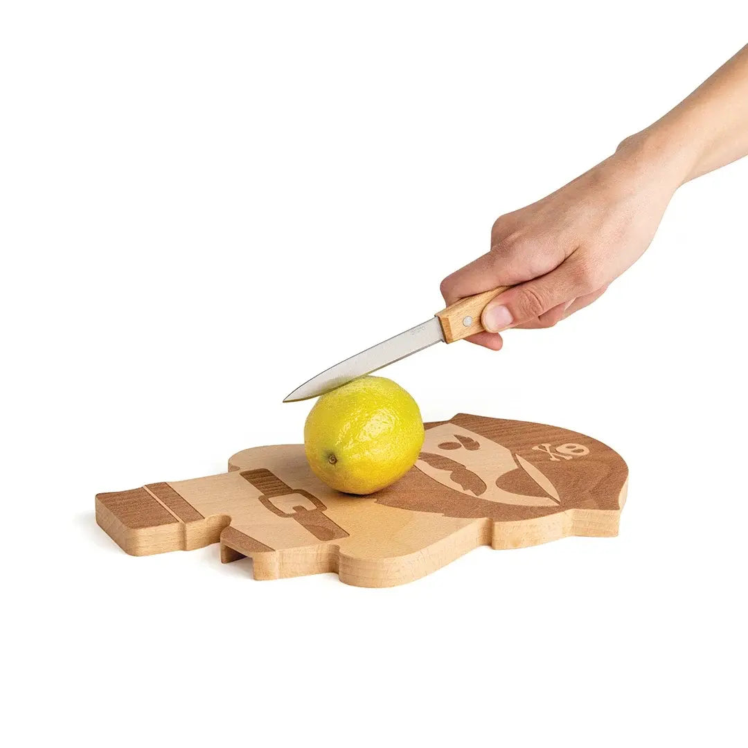a hand holding a knife over a lemon on a cutting board