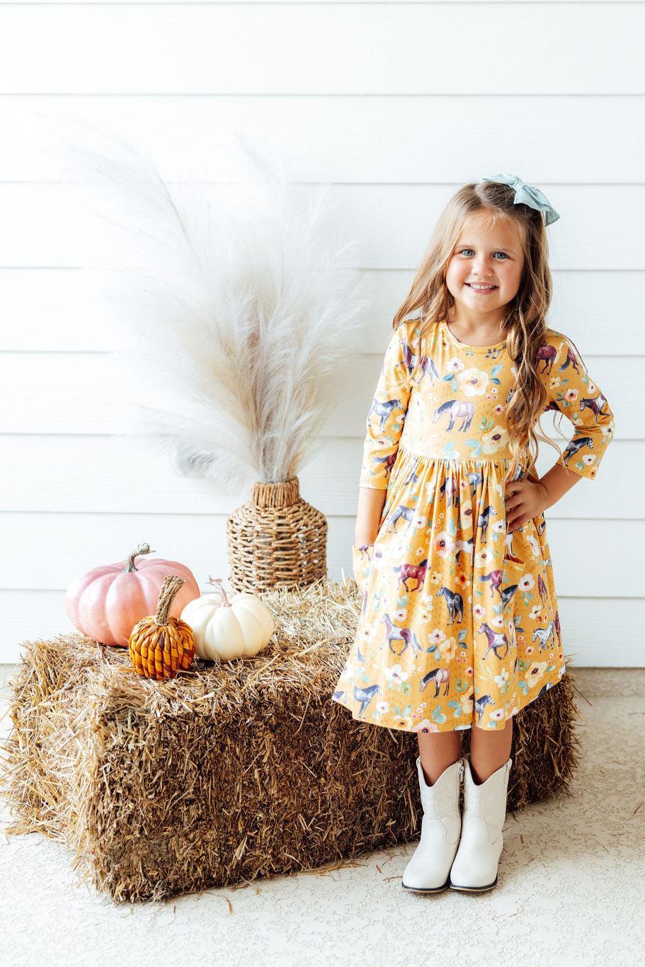 a girl standing in front of a hay bale