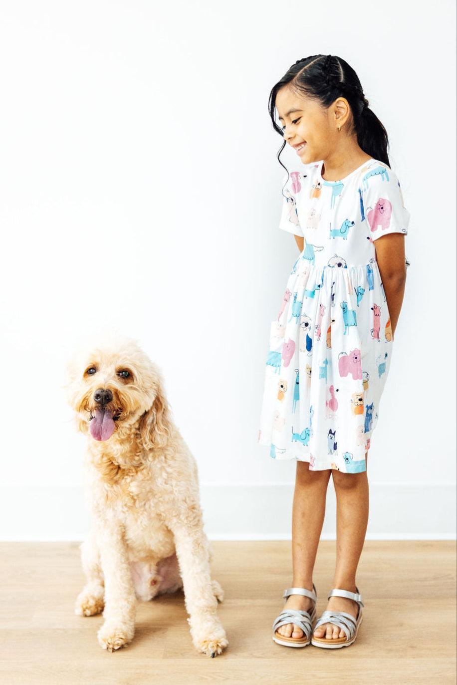 a girl standing next to a dog