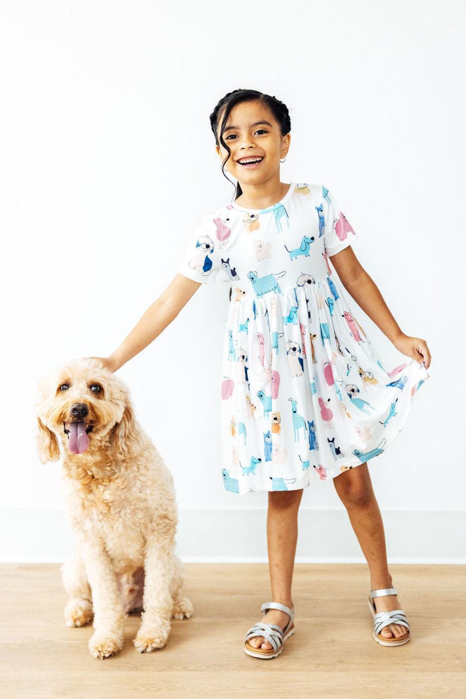 a girl standing next to a dog