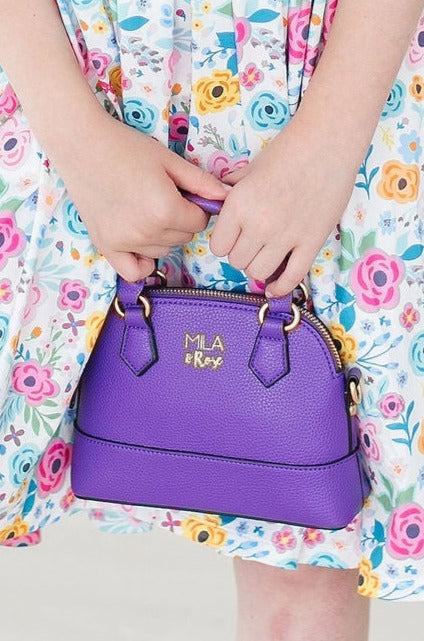 a child holding a purple purse