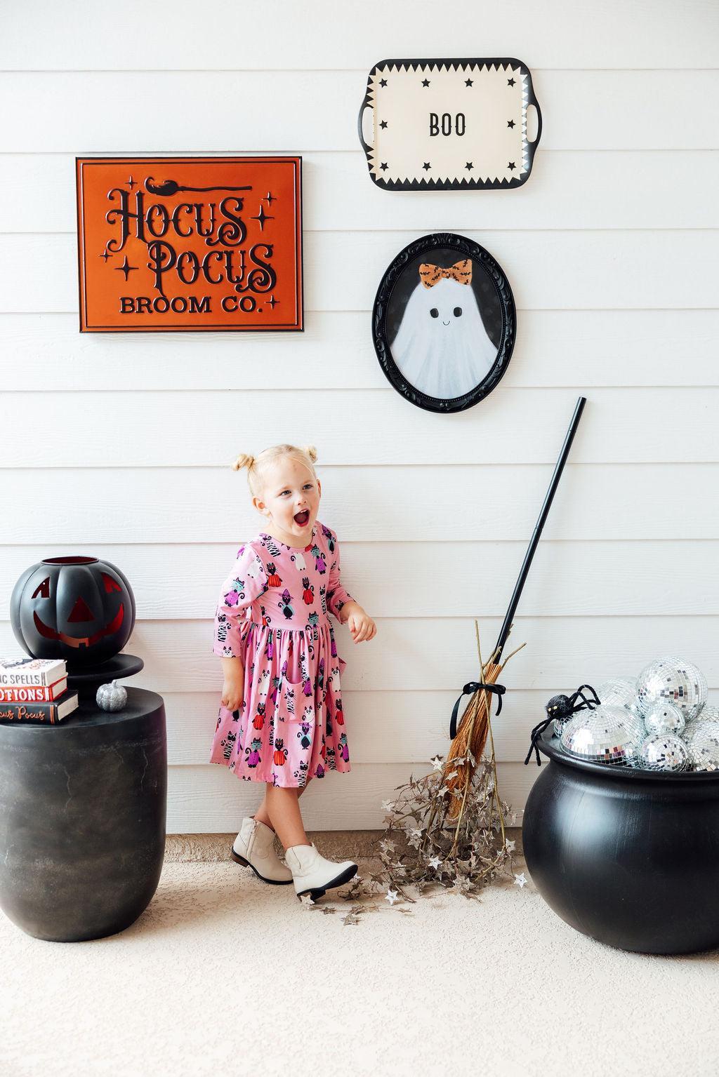 a girl standing next to a broom and a person's cauldron