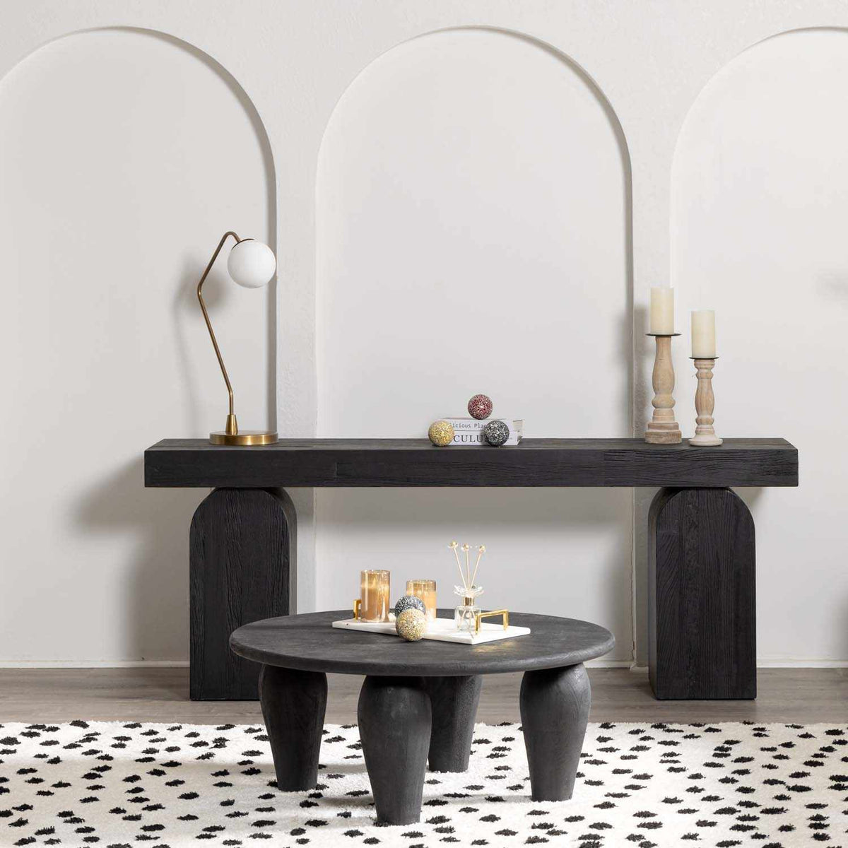 a table with candles and a lamp in front of a white wall