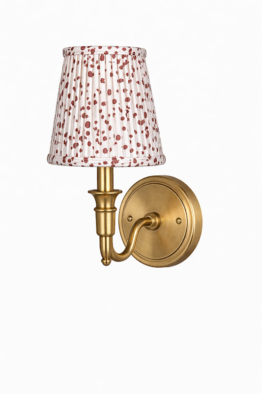 a gold wall lamp with a white shade