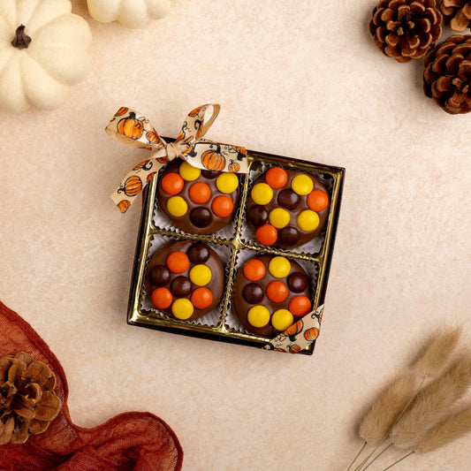 a box of candy with a bow and pine cones