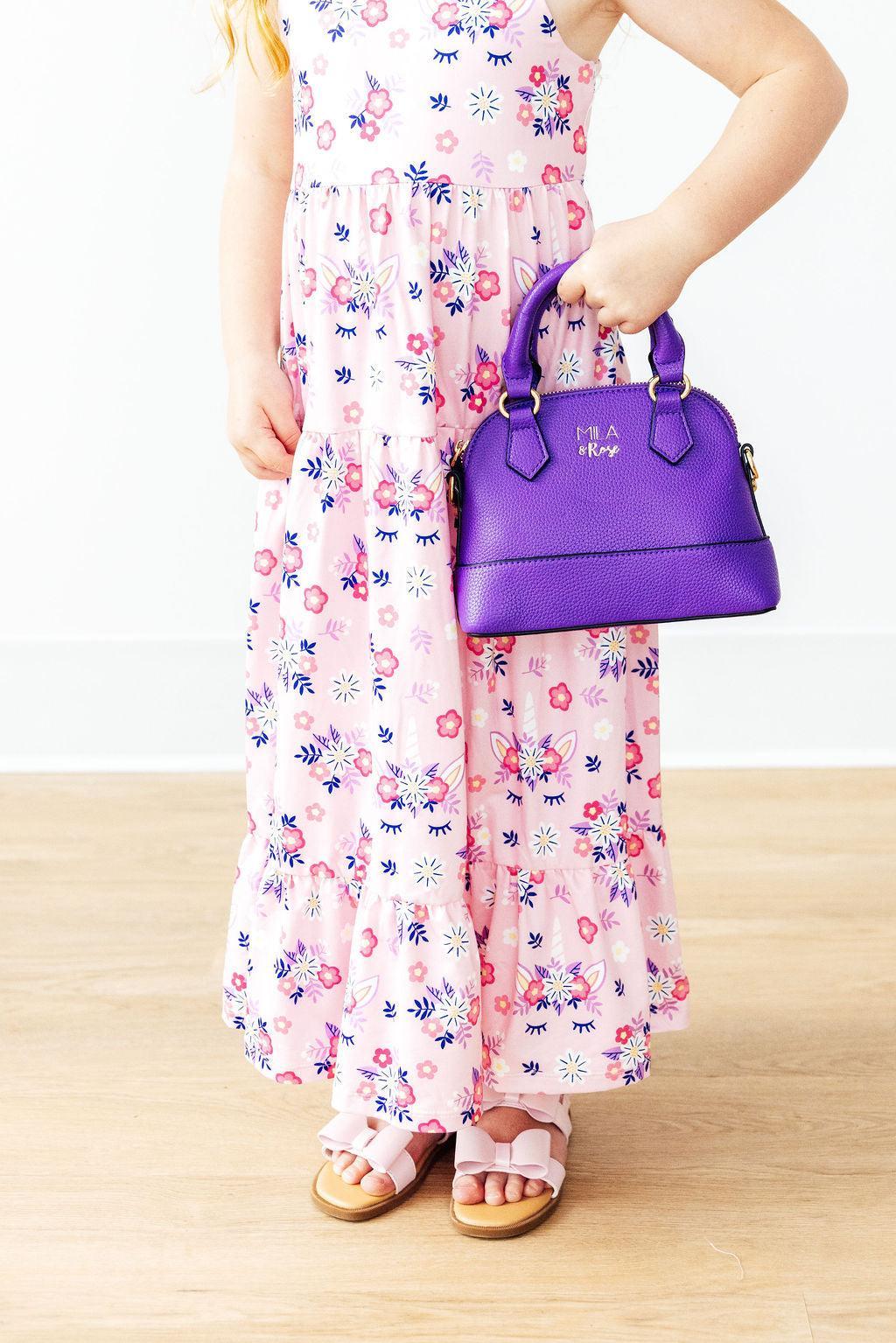 a child holding a purple purse