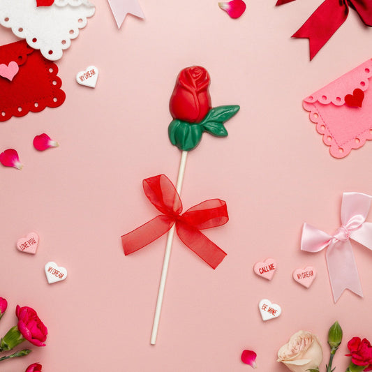 a lollipop with a red bow and ribbon surrounded by flowers