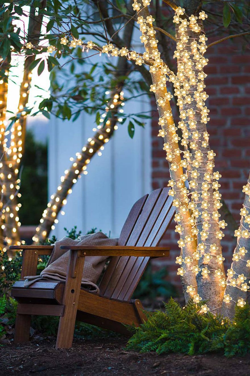 a chair with a blanket and a blanket on it next to a tree with lights