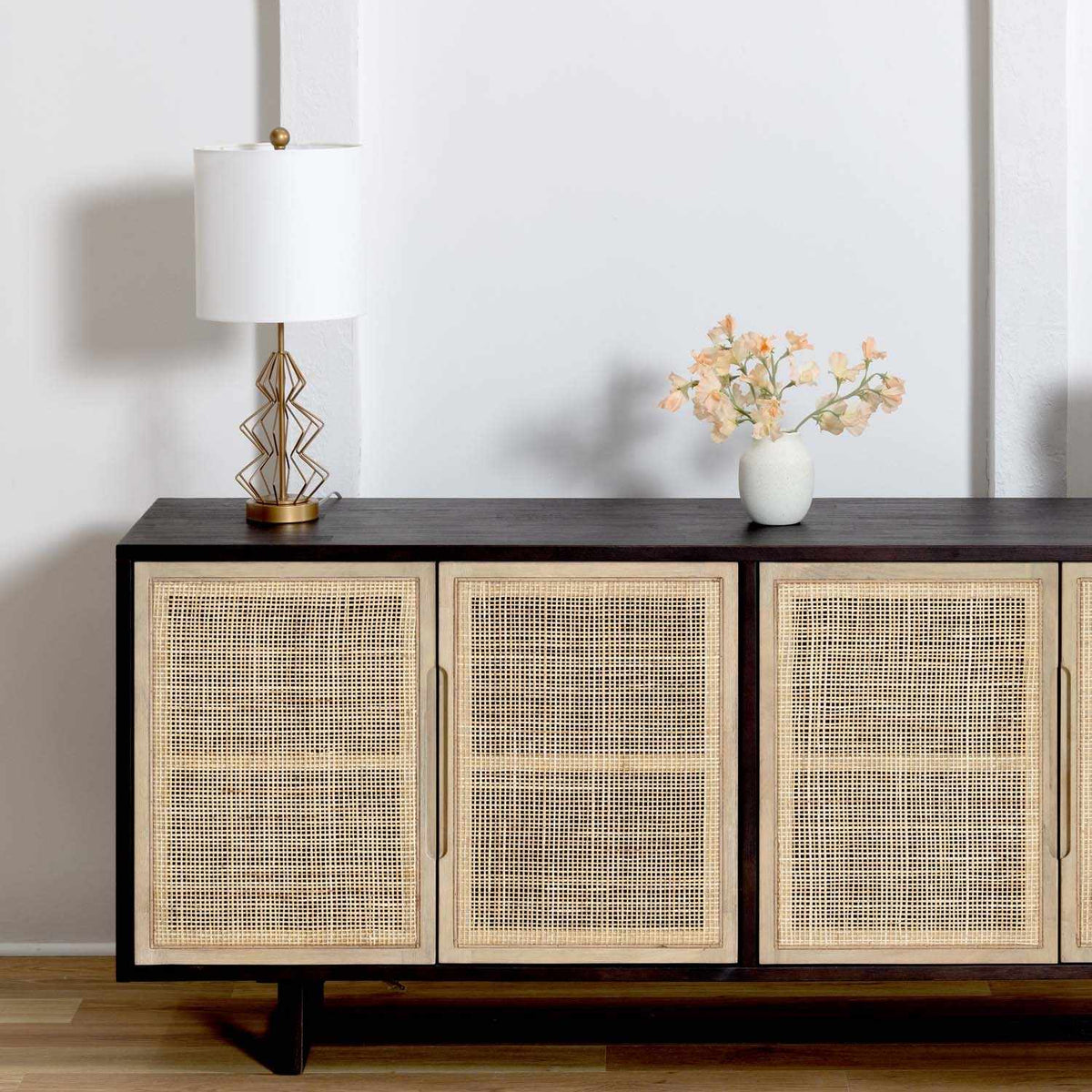 a sideboard with a lamp and flowers on it