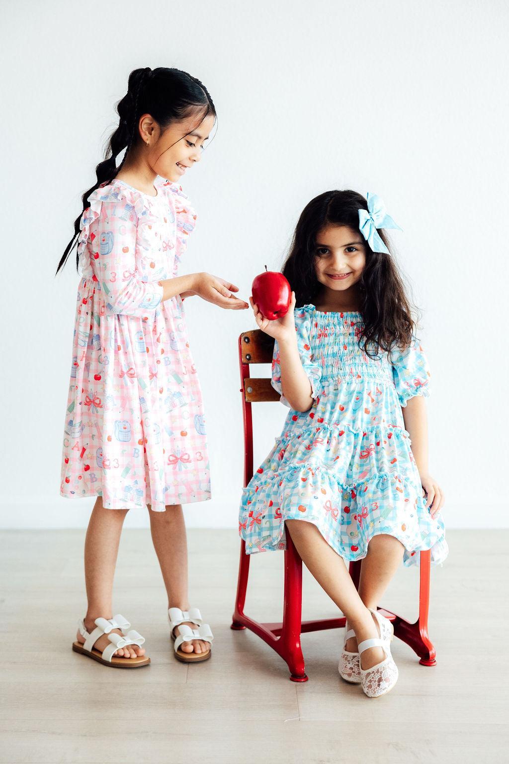 two girls sitting on a chair holding an apple