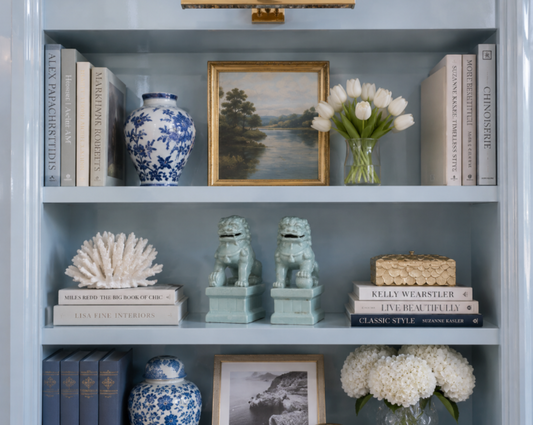 a shelf with books and vases and flowers