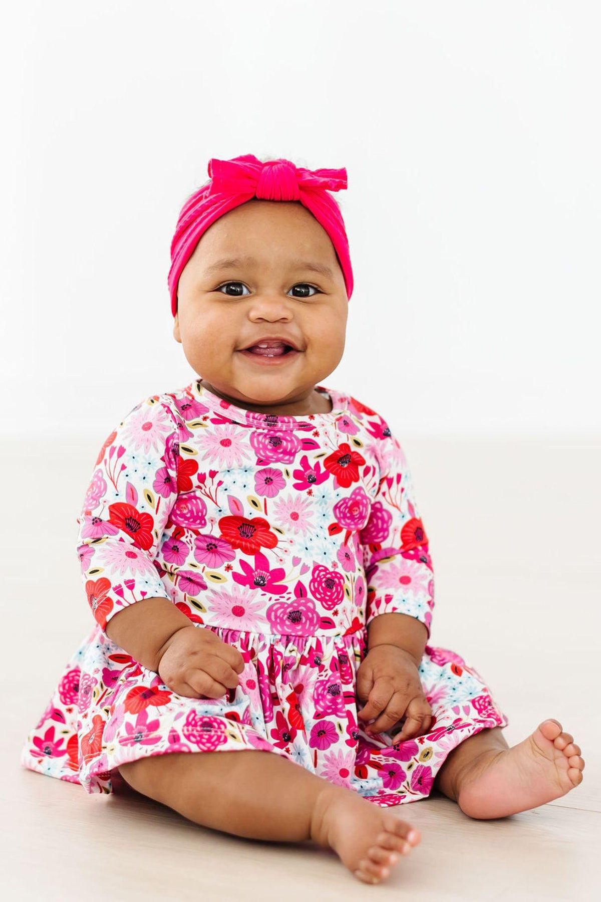 a baby girl wearing a pink headband and dress