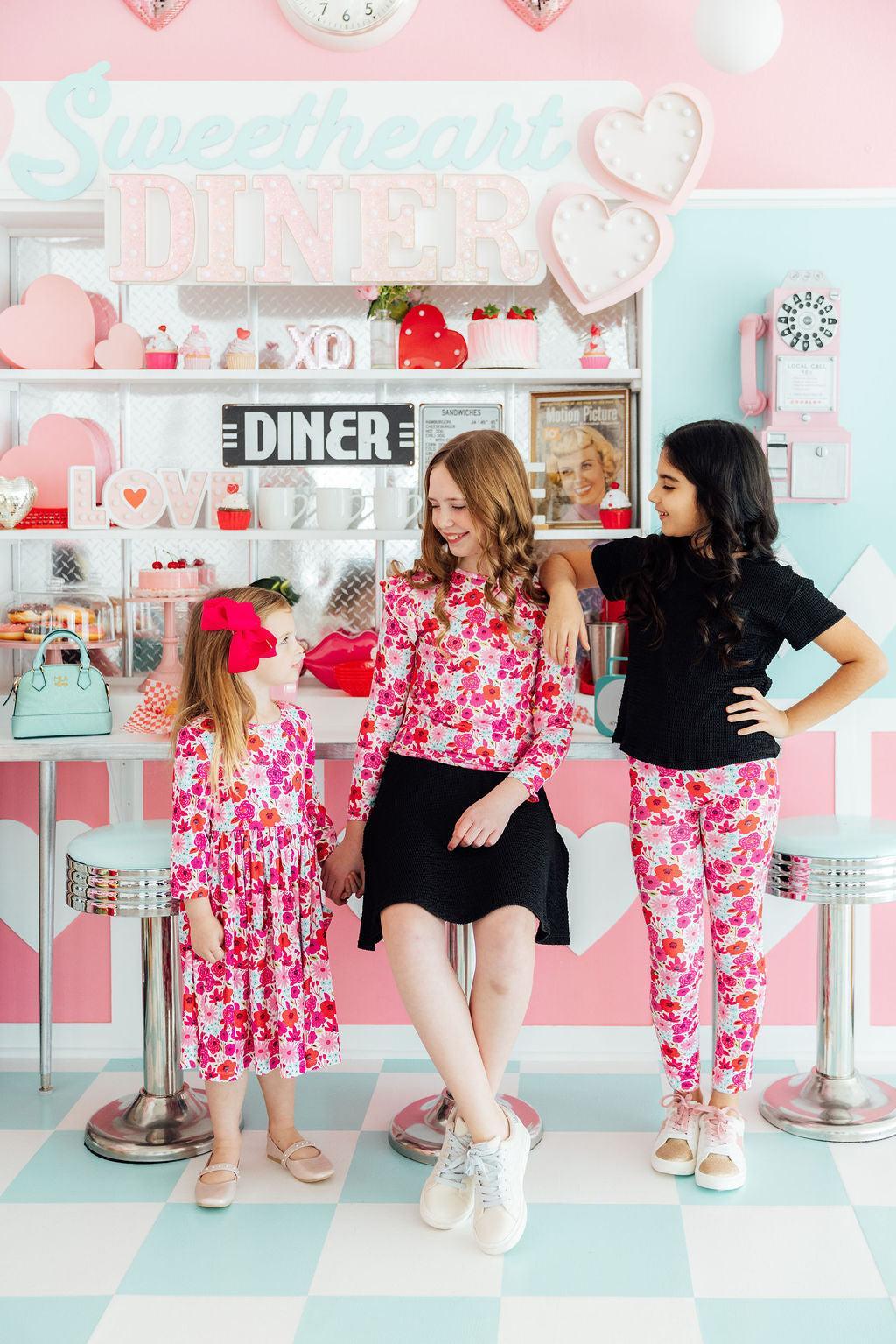 a group of girls standing in front of a pink and white counter
