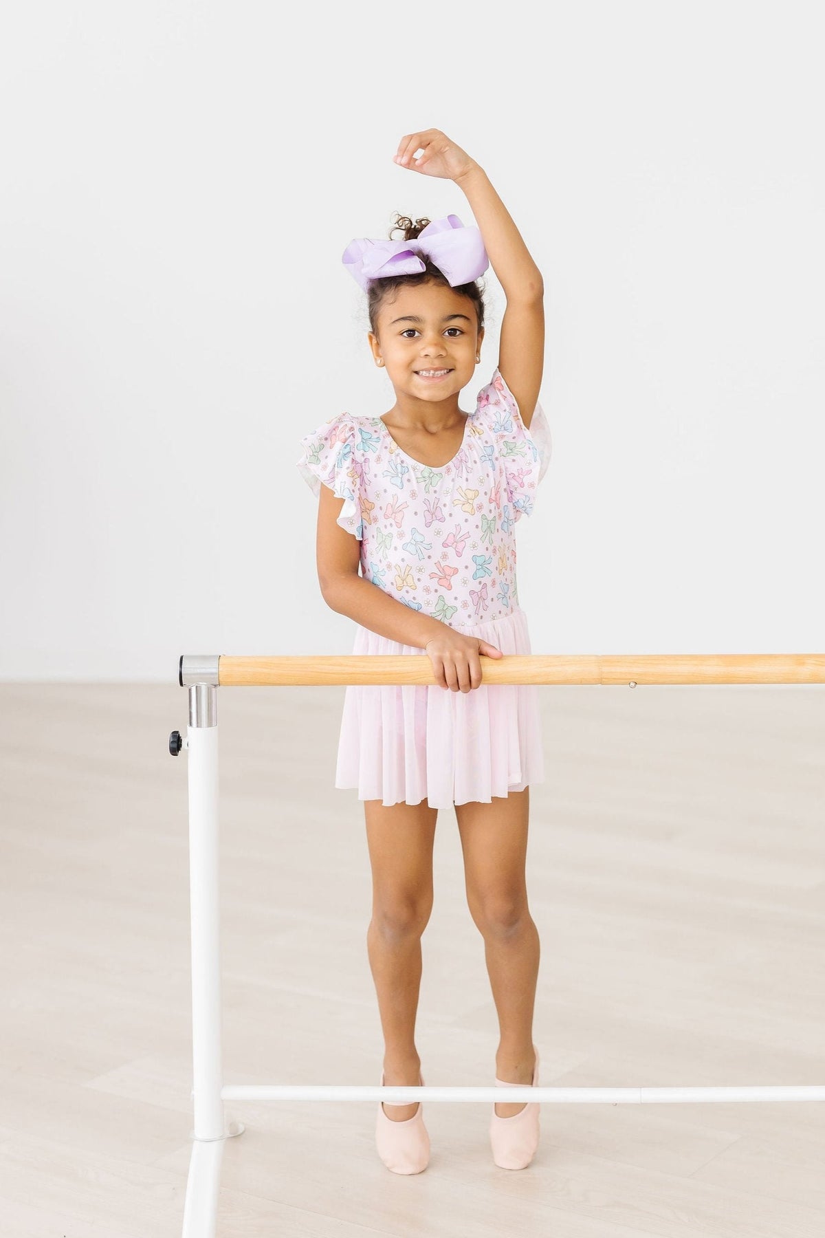 a girl in a pink dress holding a pole