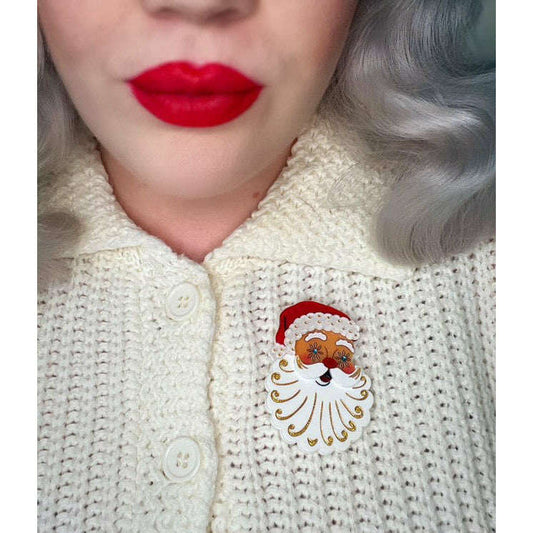 a woman wearing a white sweater with a santa claus pin