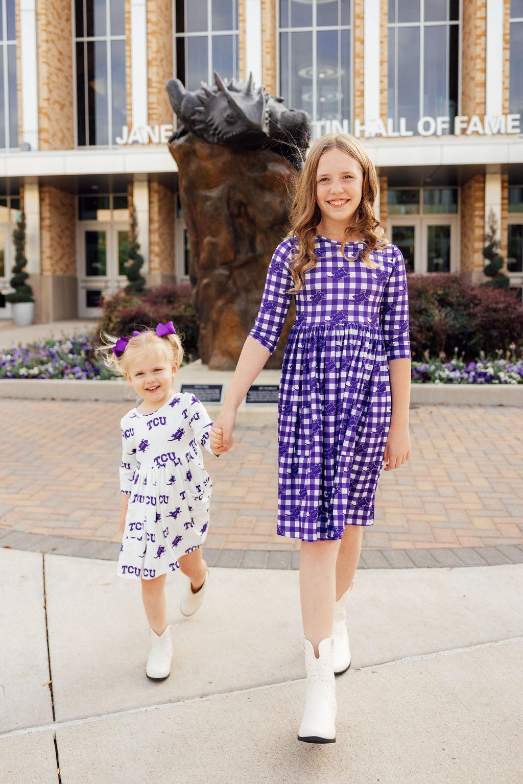 two girls holding hands and walking on a sidewalk