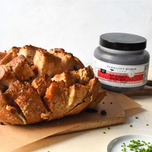 a loaf of bread on a cutting board next to a jar of food