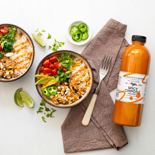 a bowl of food with a fork and a bottle of hot sauce