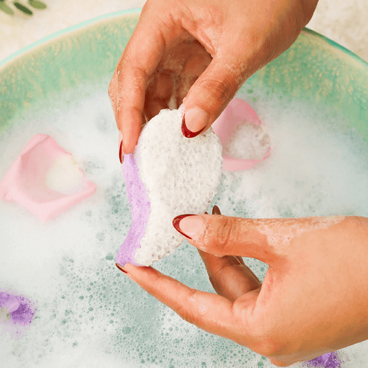 a person washing a pink and white sponge