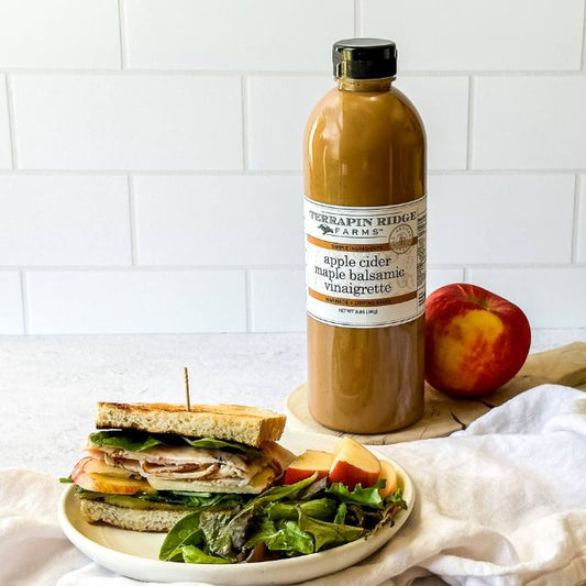 a plate of salad and a sandwich with a bottle of apple juice