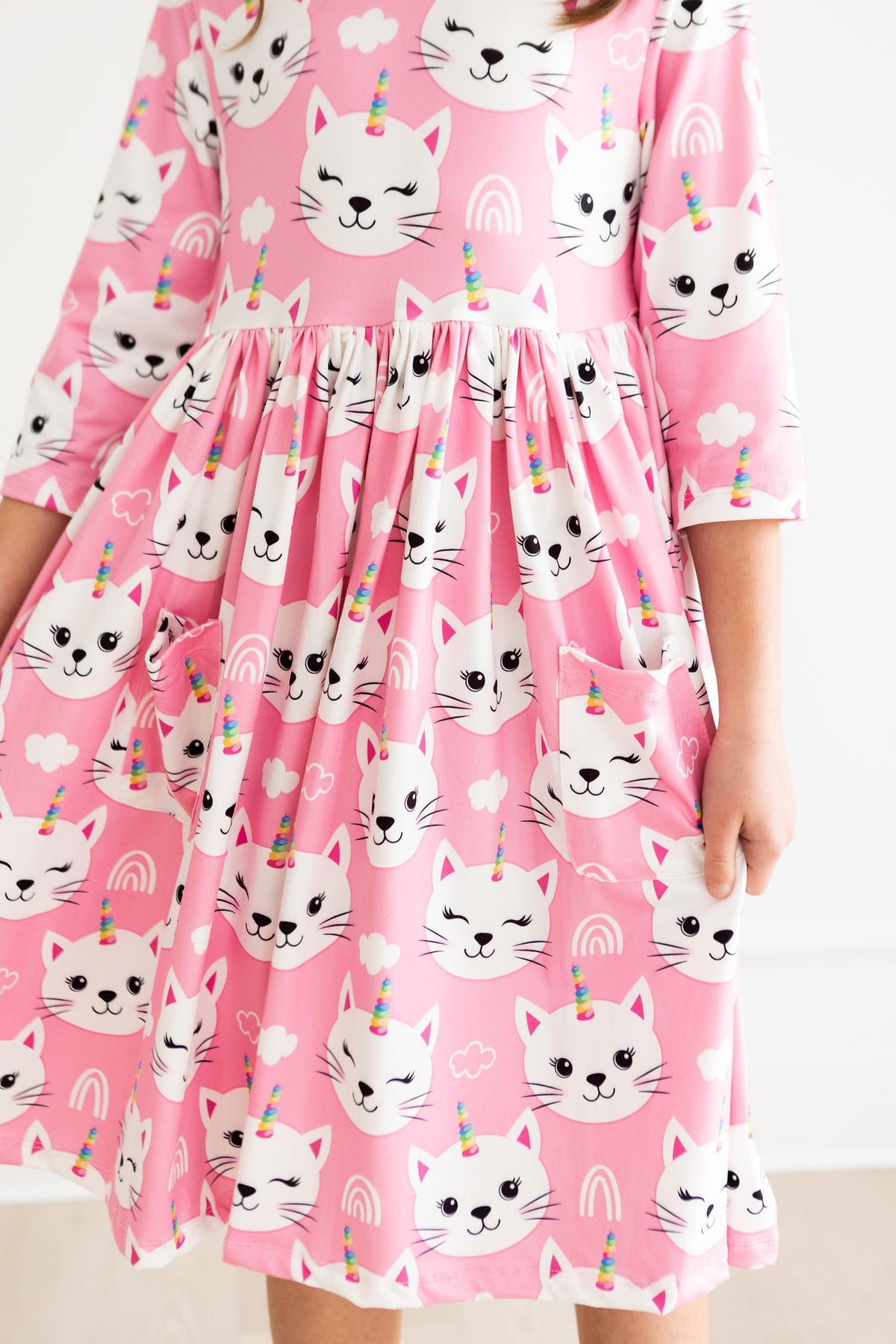 a girl wearing a pink dress with cats and unicorns