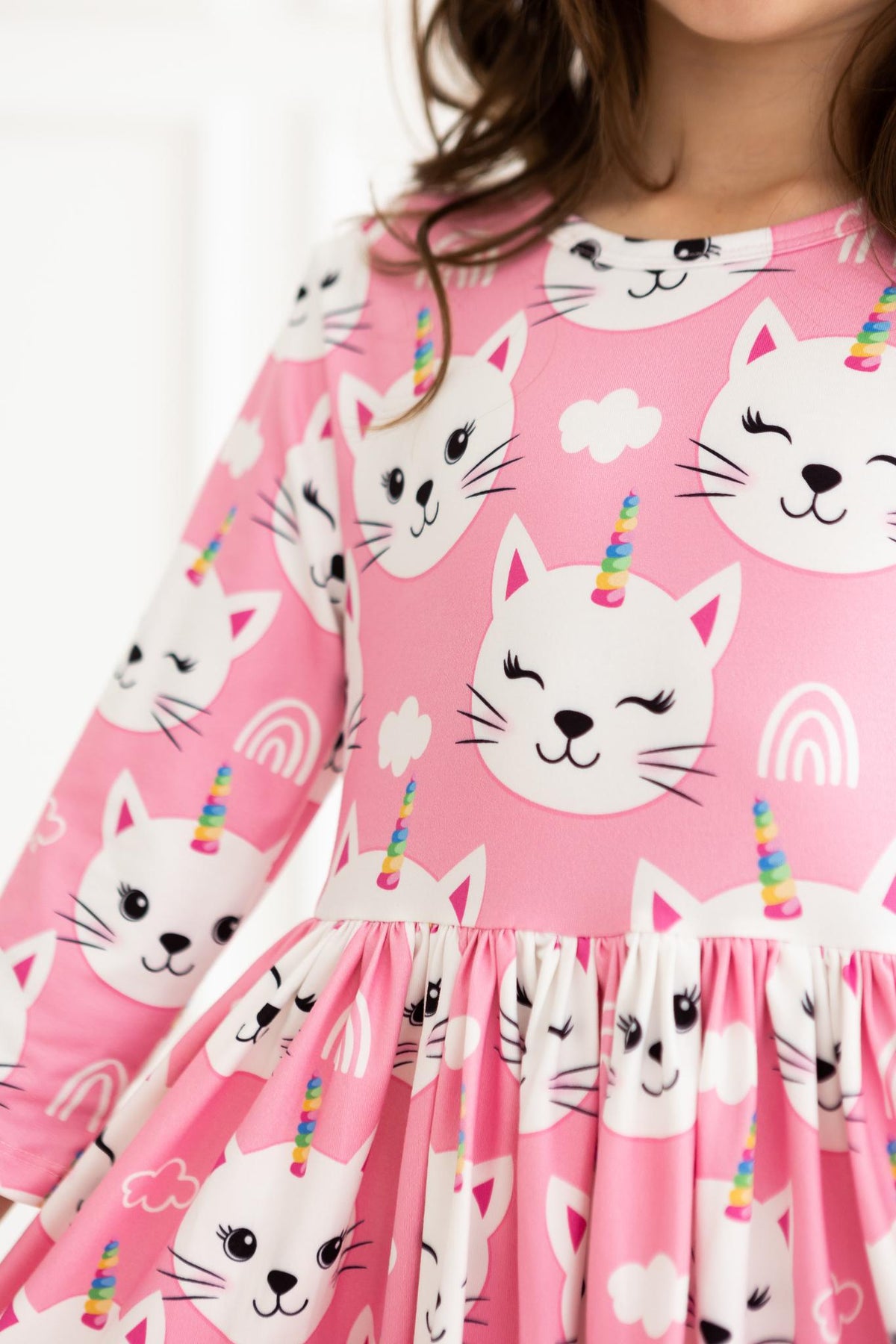 a girl wearing a pink dress with cats and unicorns