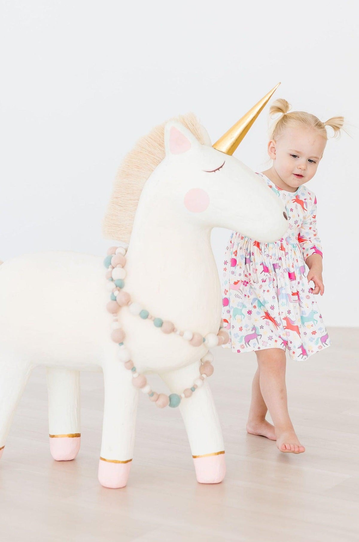 a girl standing next to a toy unicorn