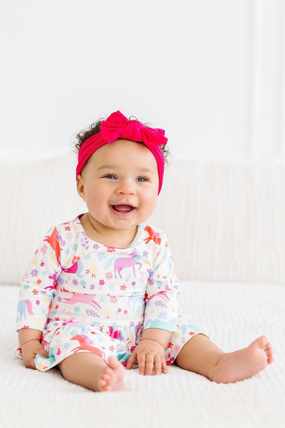 a baby smiling with a pink bow on her head