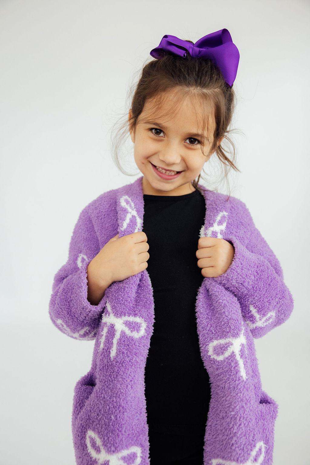 a girl wearing a purple robe and a bow