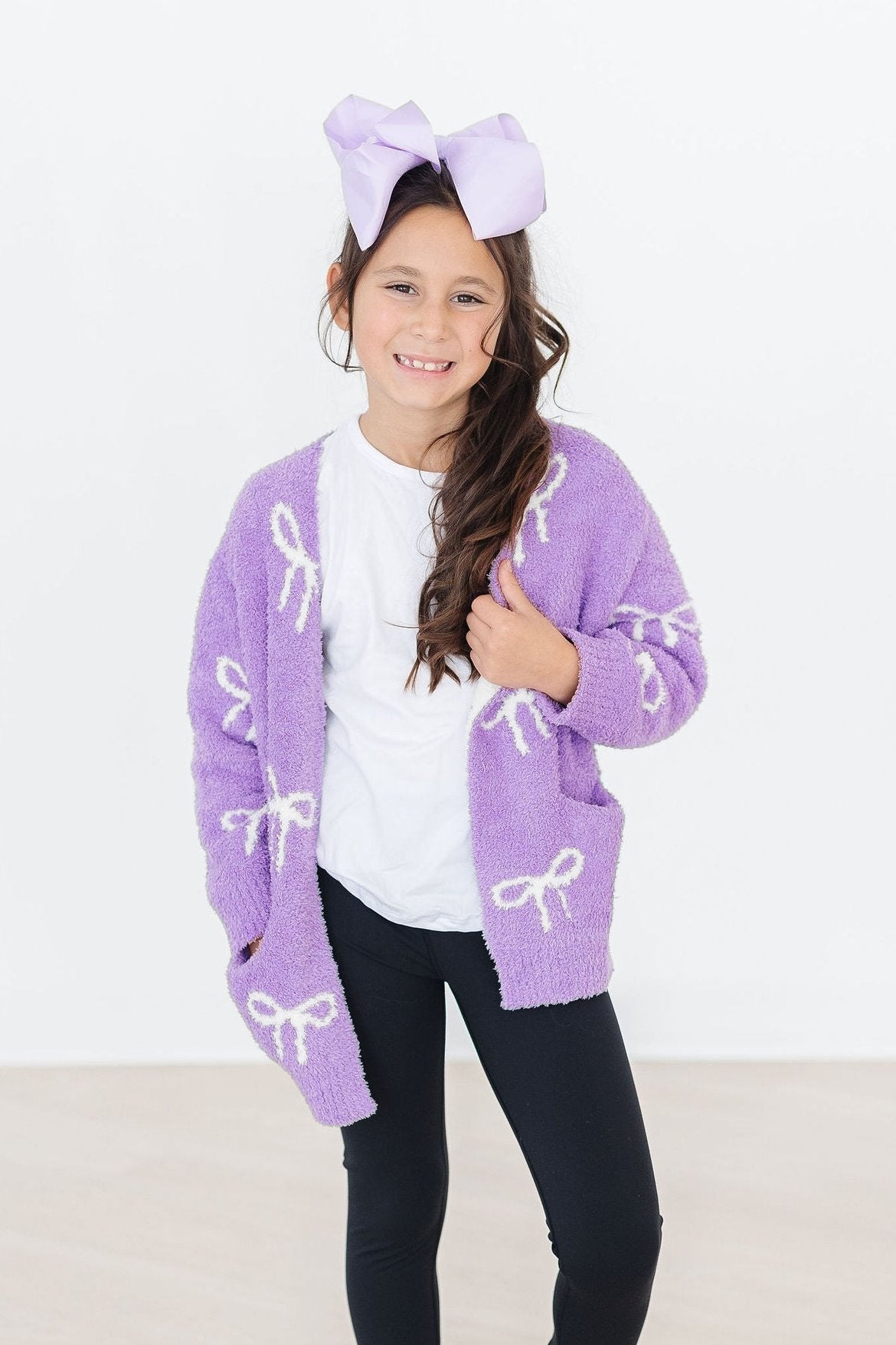 a girl wearing a purple sweater and bow