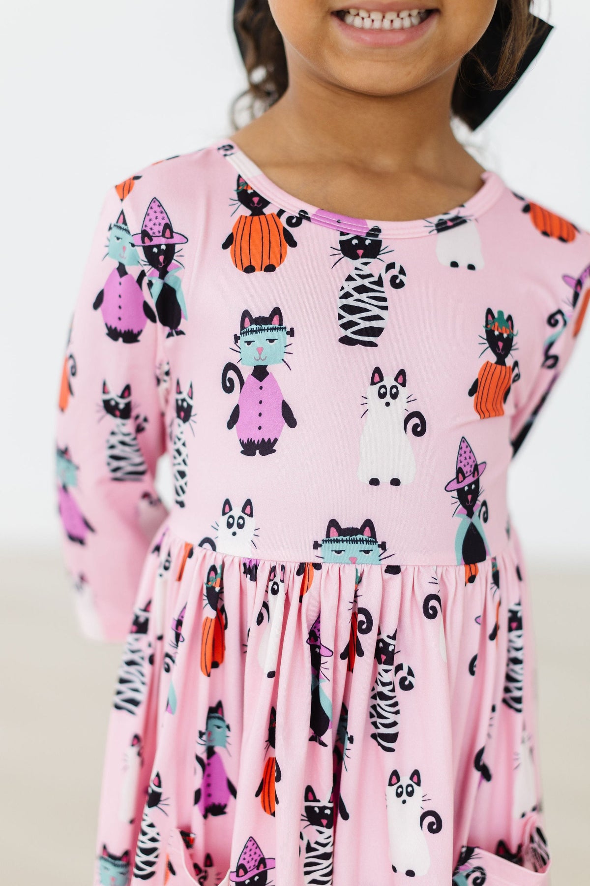 a child wearing a pink dress with cats on it