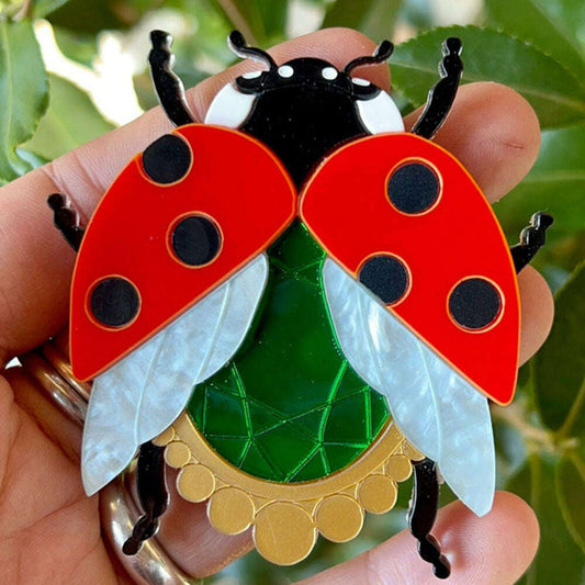 a hand holding a ladybug brooch