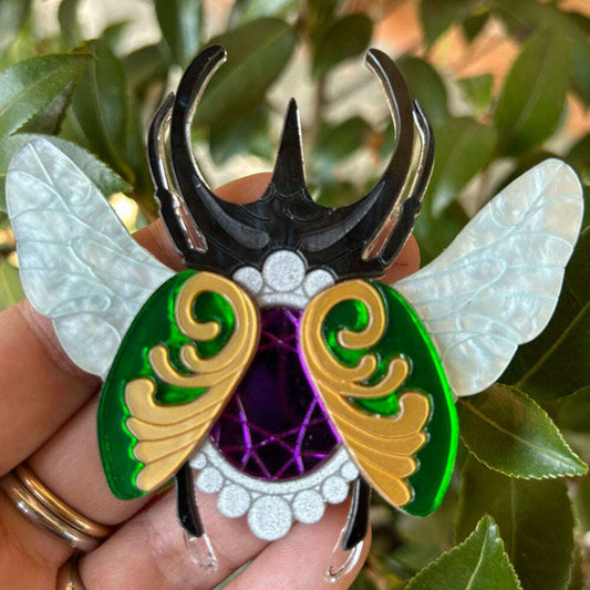 a hand holding a bug brooch