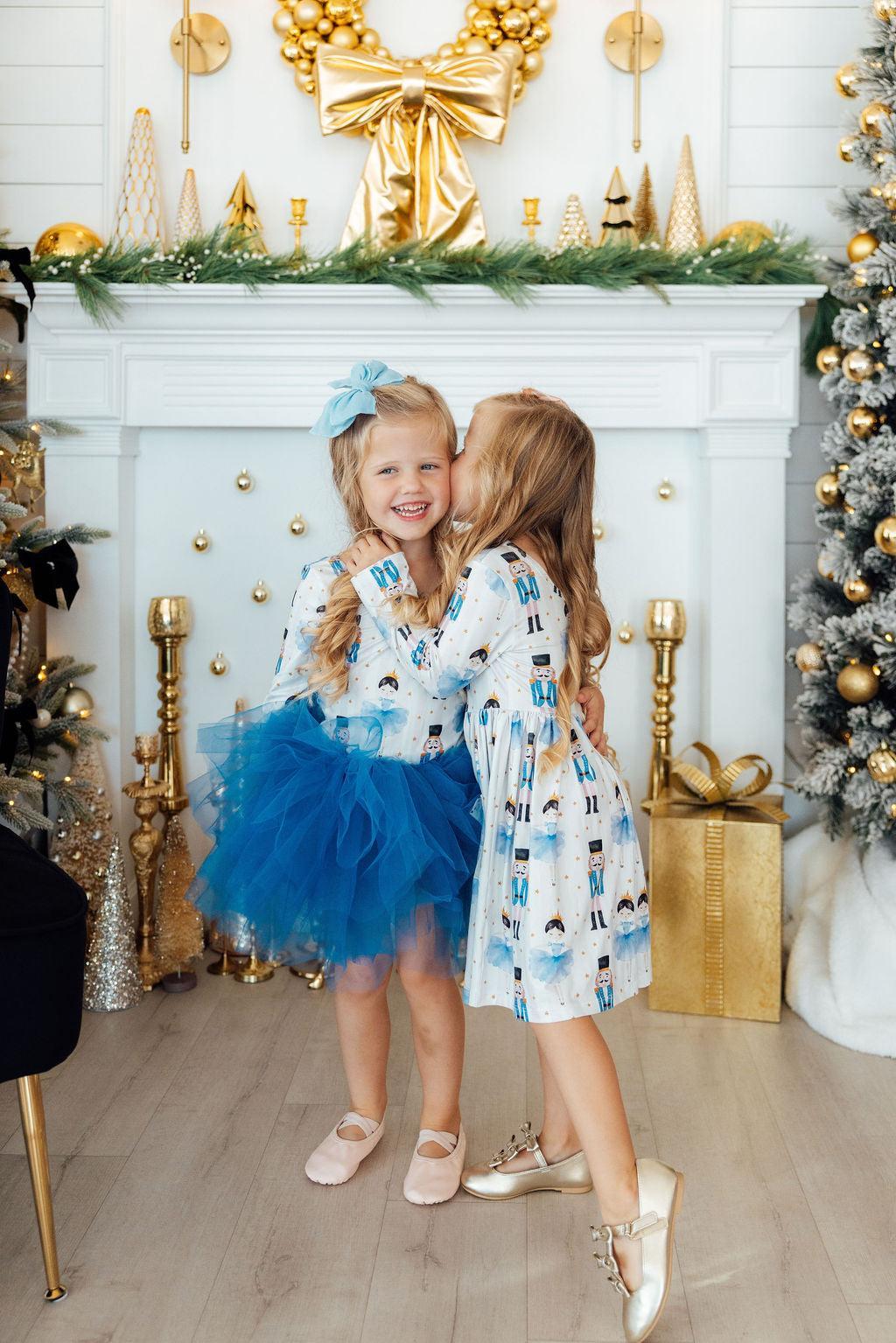 two girls hugging in front of a fireplace