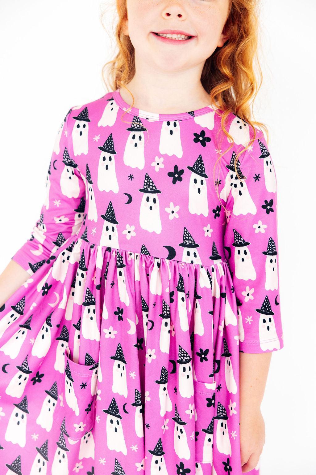 a girl wearing a pink dress with white ghosts on it