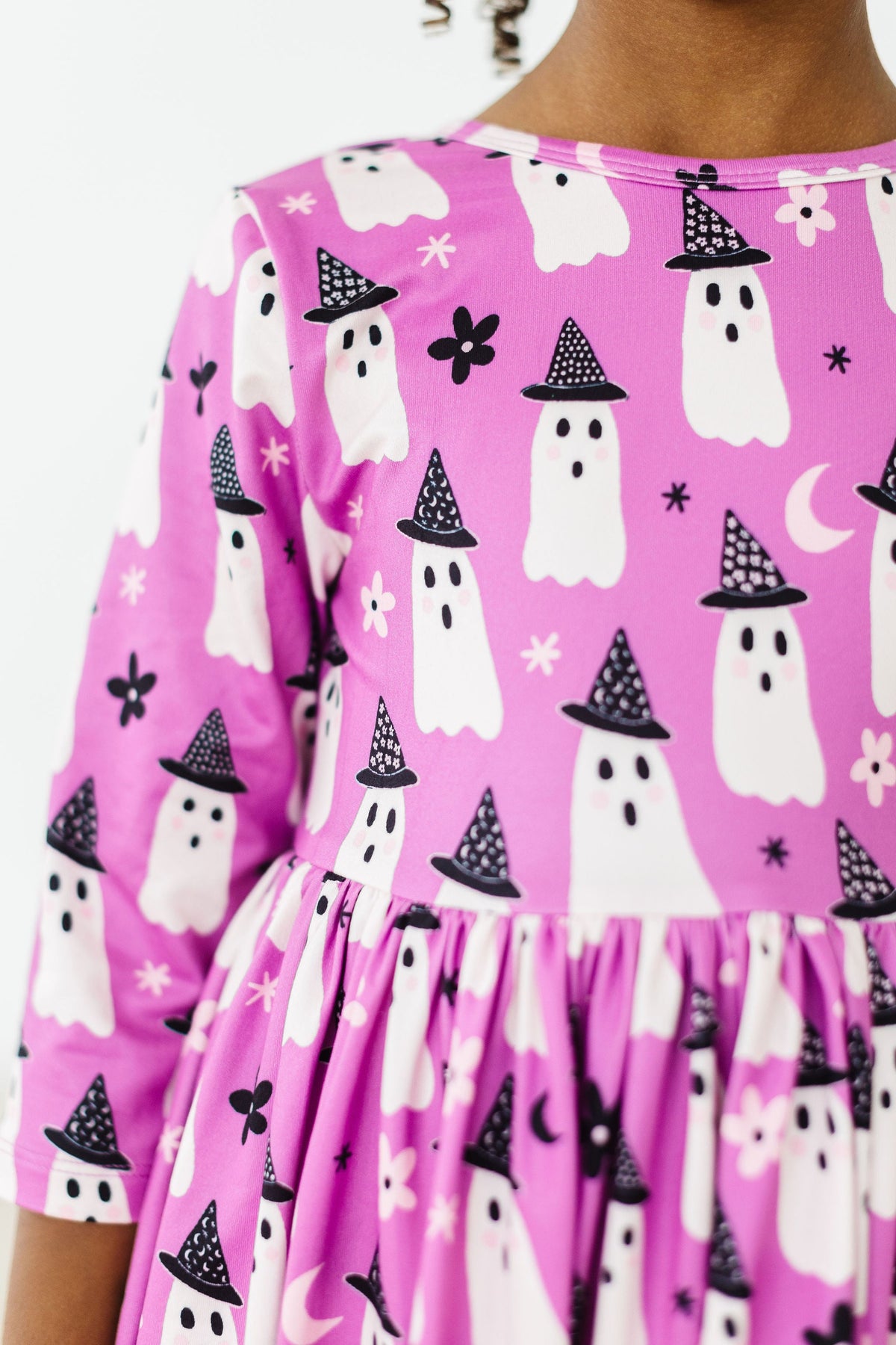 a girl wearing a pink dress with white ghosts on it