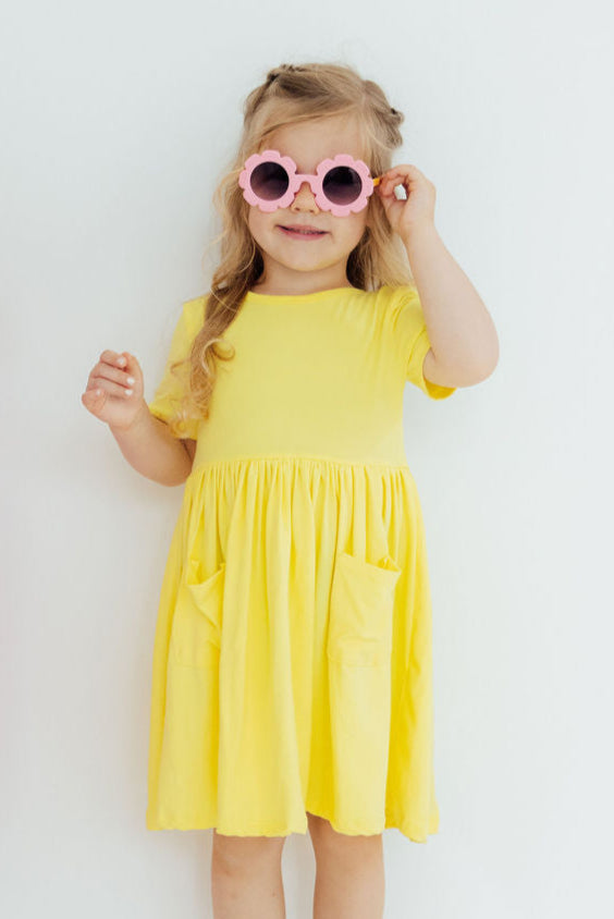 a girl wearing a yellow dress and pink sunglasses