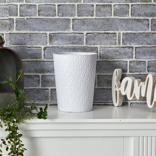 a white vase and plant on a white shelf