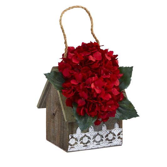 a wooden birdhouse with red flowers