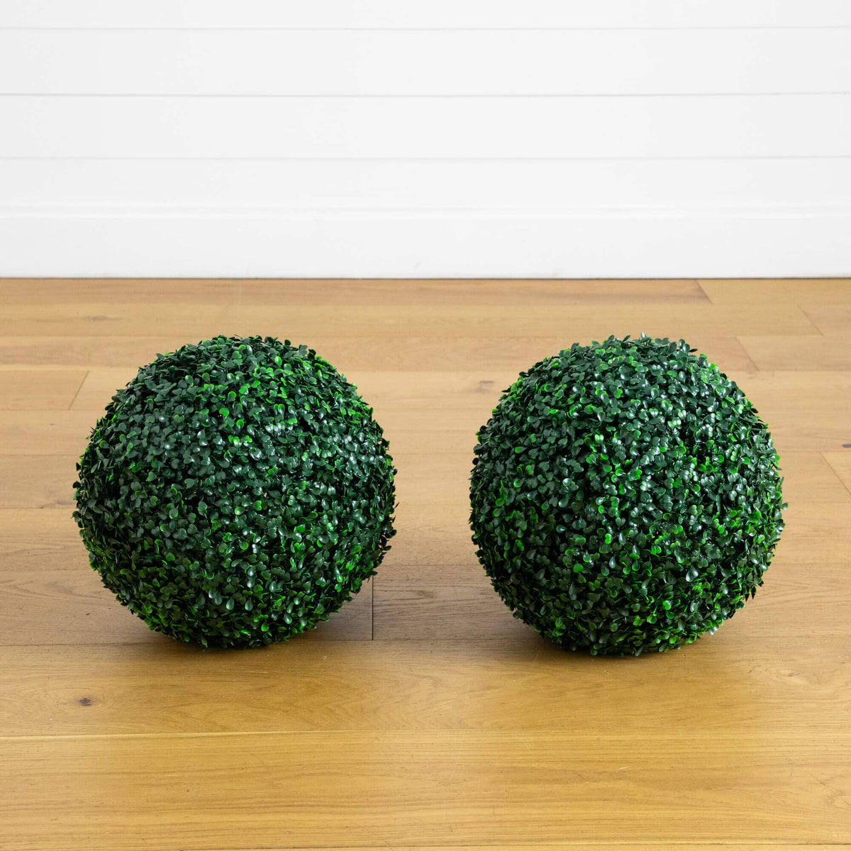 two green balls on a wood floor