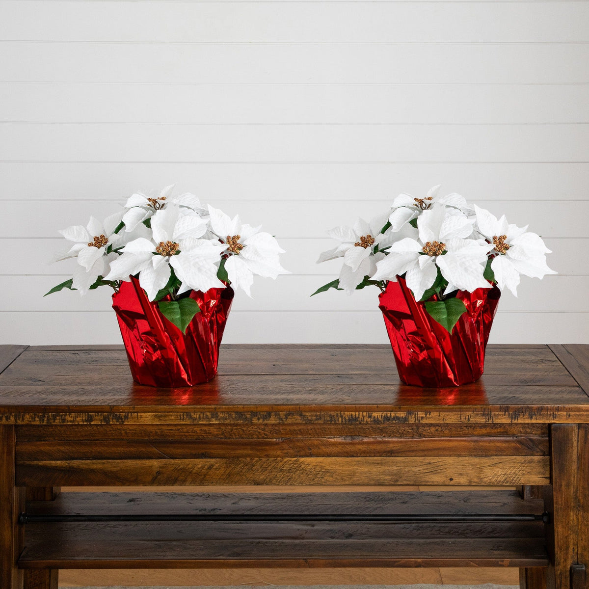 two white flowers in red foil pots on a wooden table