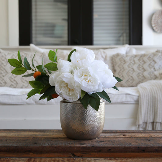 a white flowers in a silver vase on a wooden table