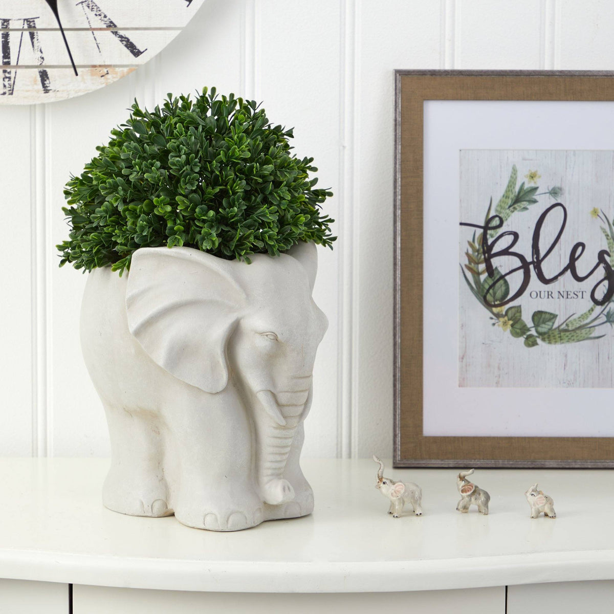 a white elephant statue with a plant in it and a picture frame