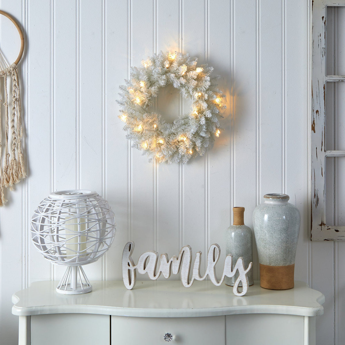 a white dresser with a wreath and a dream catcher on the wall