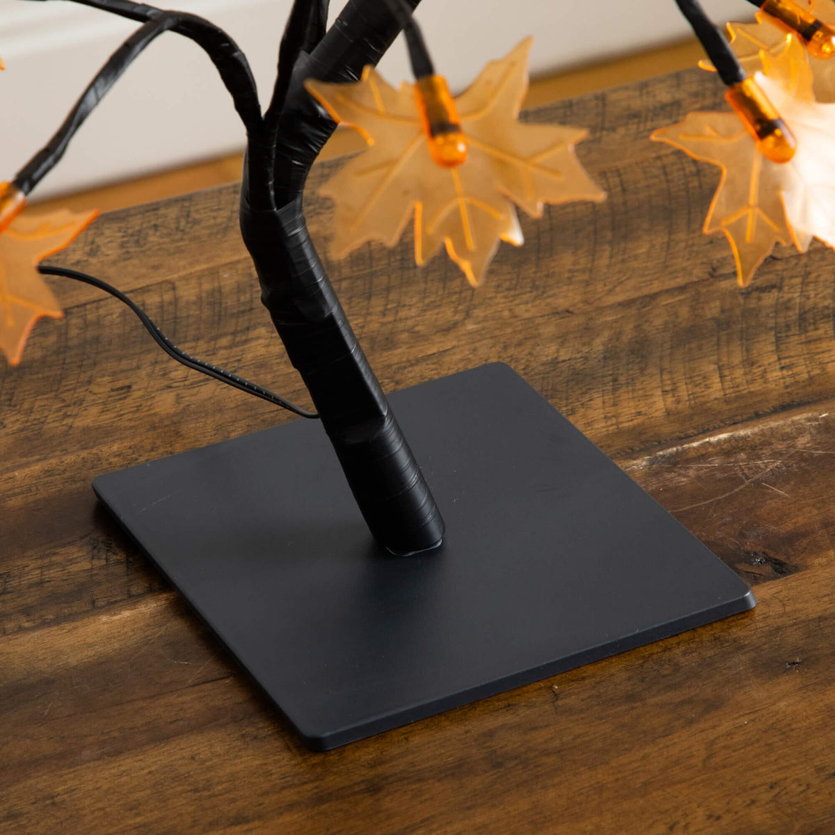 a black tree with orange lights on a wood surface
